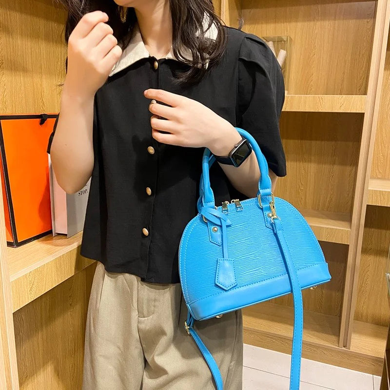 Person holding a blue handbag in a store setting